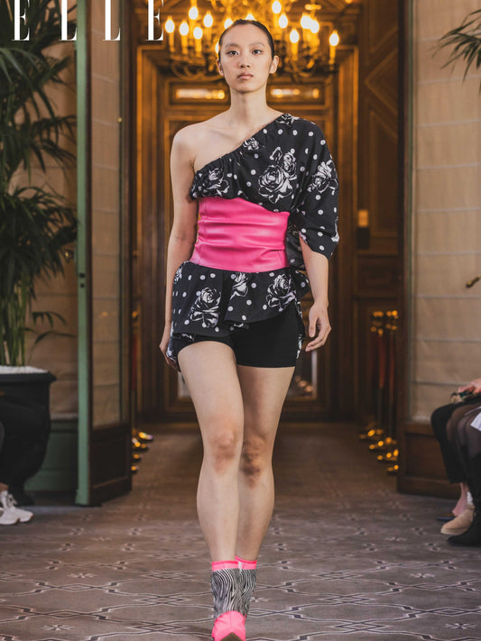 A model wearing a size adjustable black and white floral print top with a hot pink corset detail and corset backing for adjustability. 