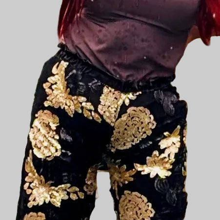 This photo shows a model wearing the black and gold size adjustable sequin pants paired with the brown Mousse top