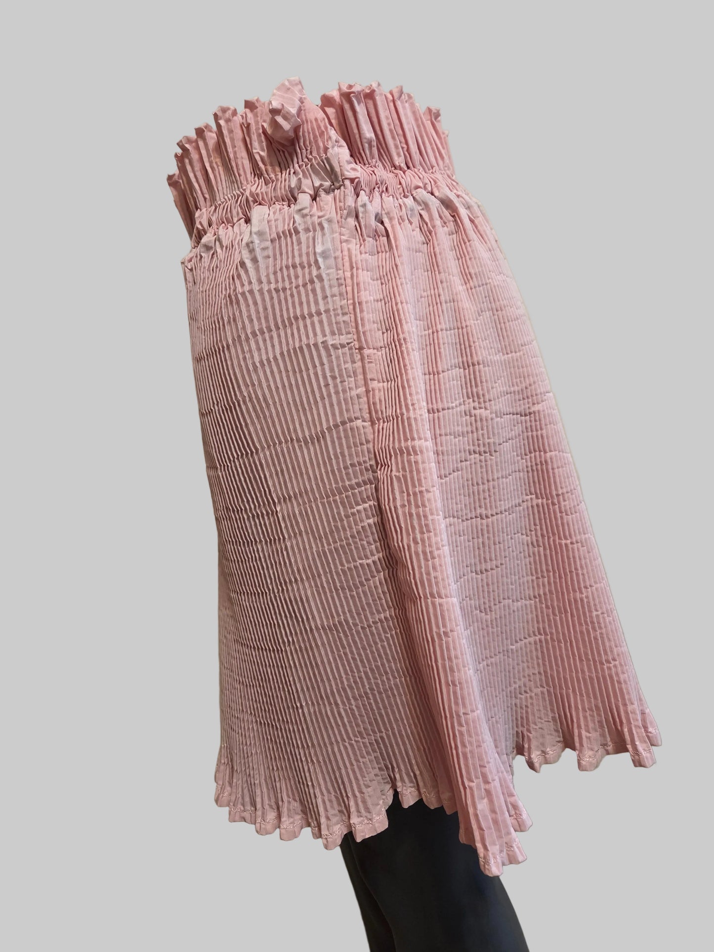 Side view of a size adjustable pink pleated skirt