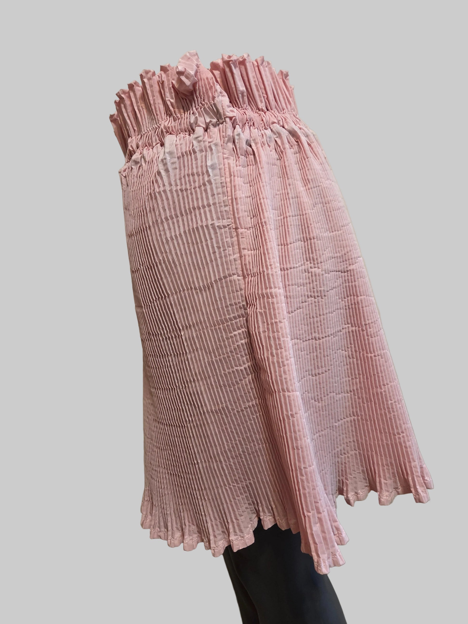 Side view of a size adjustable pink pleated skirt