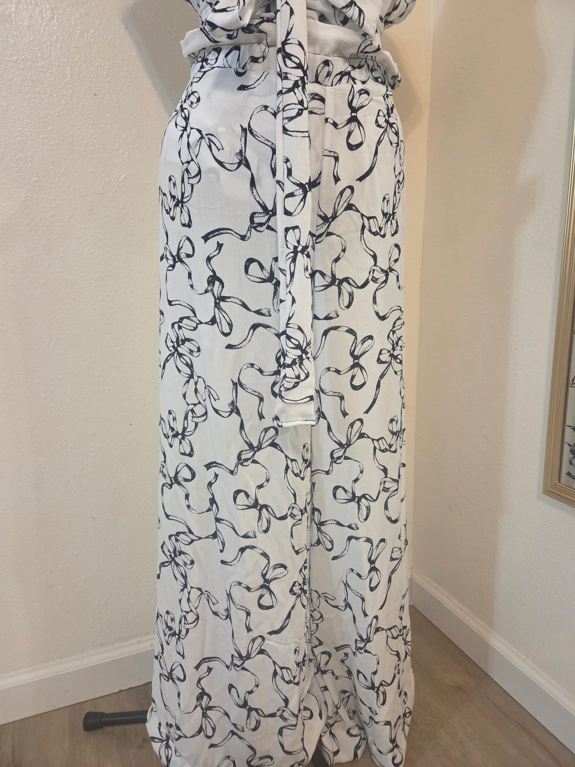 This photo shows a size adjustable pair of black and white bow pattern pants that fit multiple sizes. 