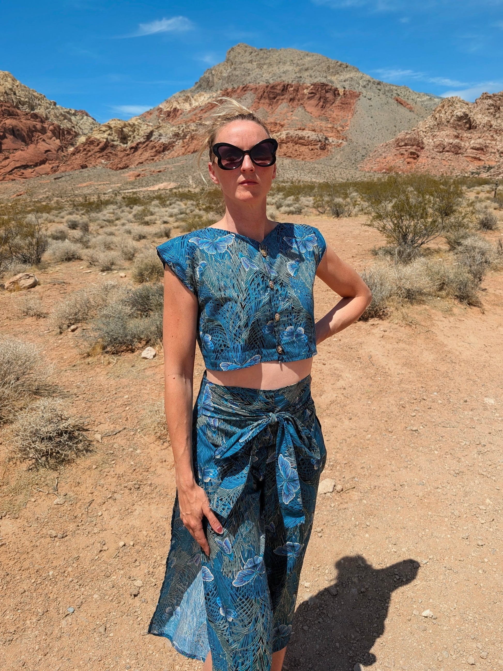 This photo shows a size adjustable two piece with a tie waistbelt as the waistband. The pattern on the fabric is a blue, moth themed cotton fabric. The top is a crop top with gold buttons.