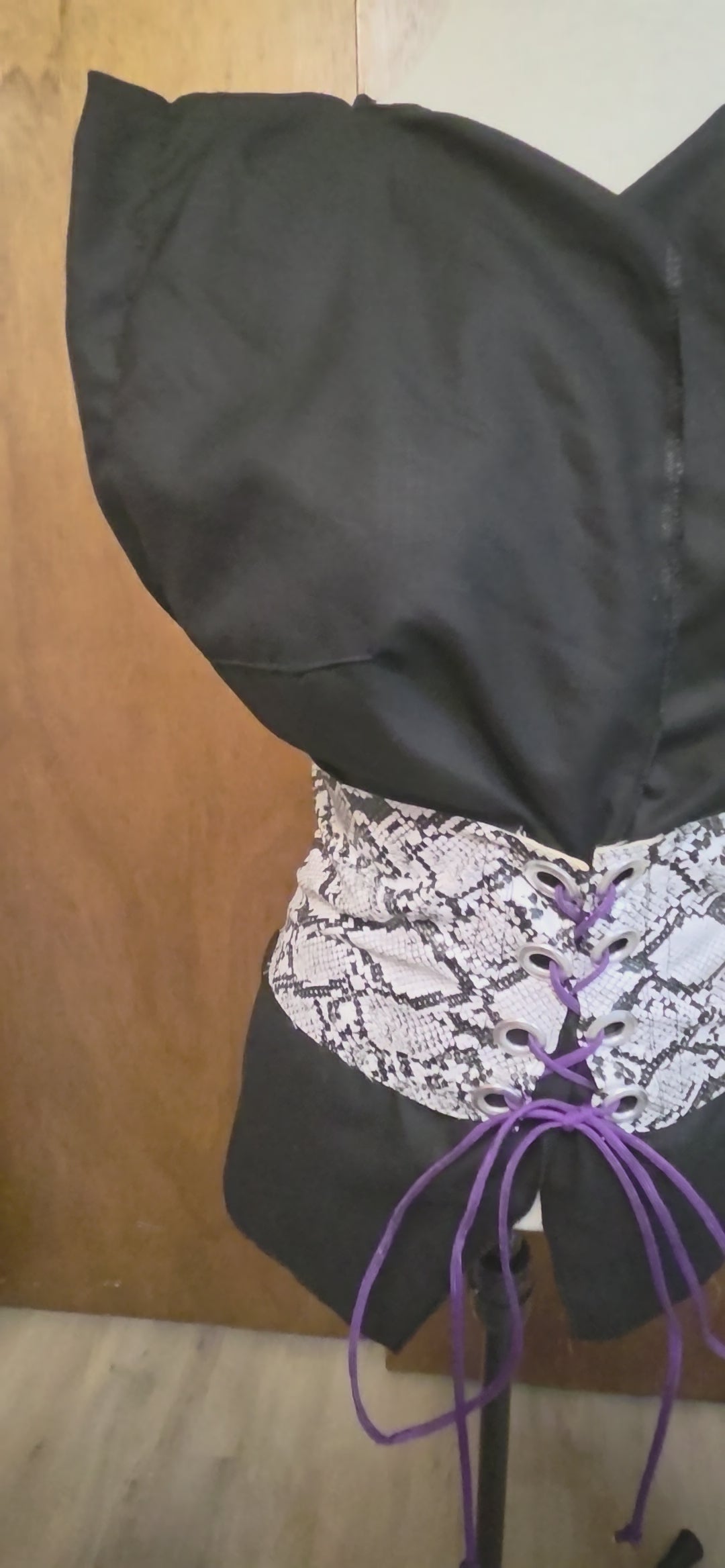 This video shows a black linen shirt that is size adjustable by way of a faux snake skin corset on top. 