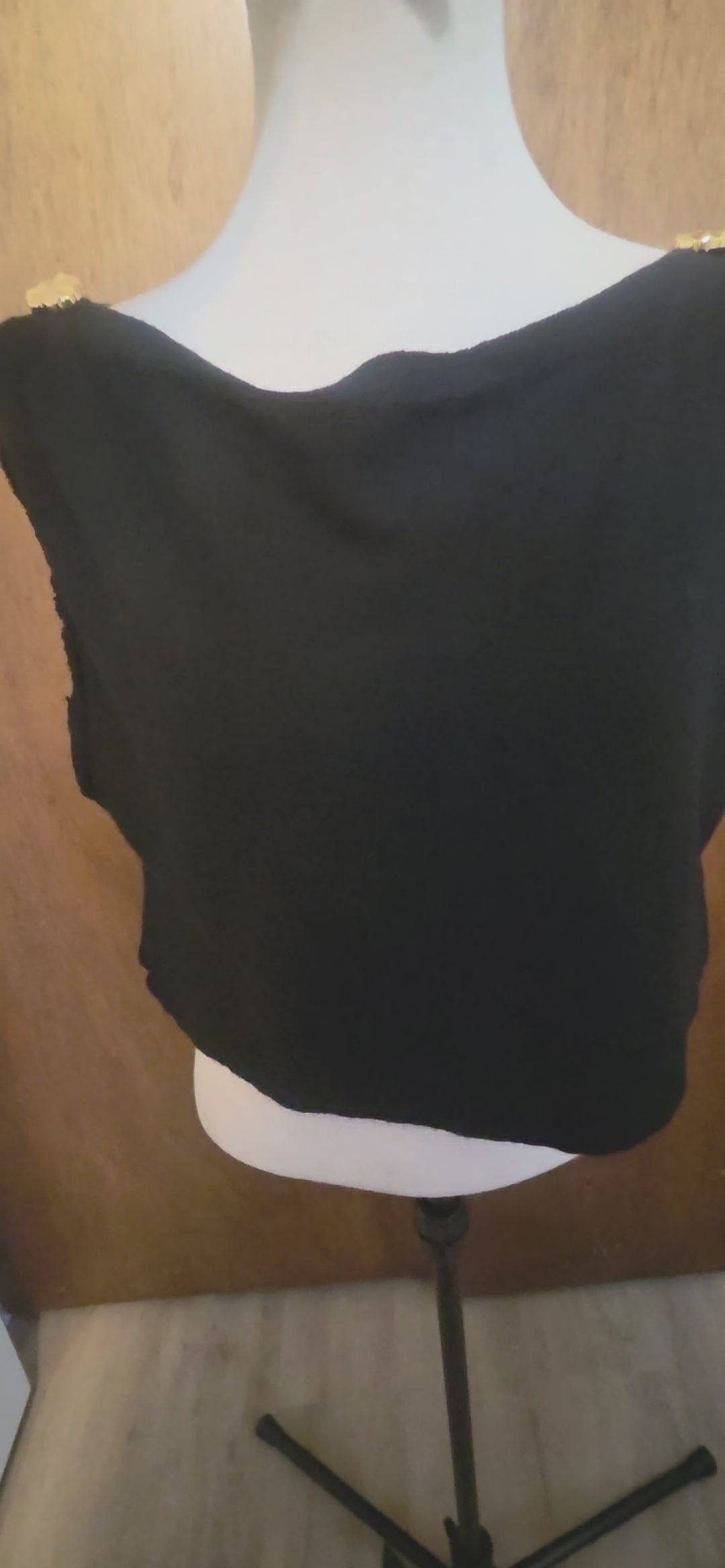 This photo shows a size adjustable black top made of soft knit, black fabric that is both stretchy and has the capability of tying at the back to accomplish different sizes. 